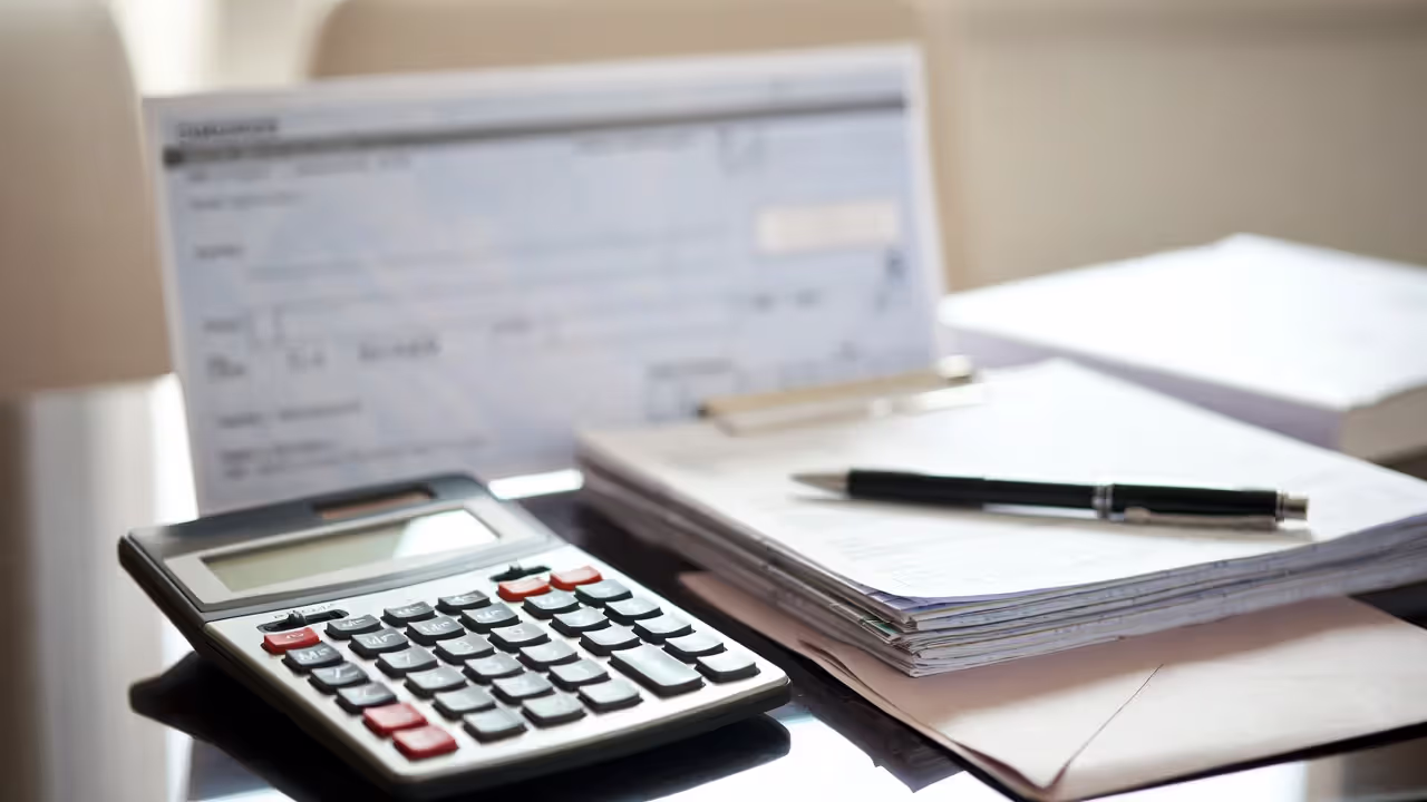 Calculator, financial reports, and a payment document on a desk, illustrating class action settlement distribution.