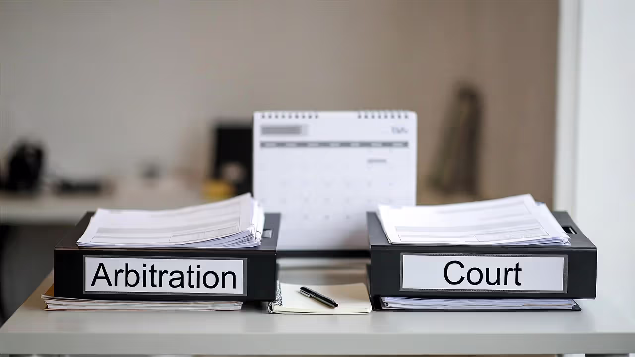 Two document folders representing arbitration and court paths on an office desk, labels blurred.