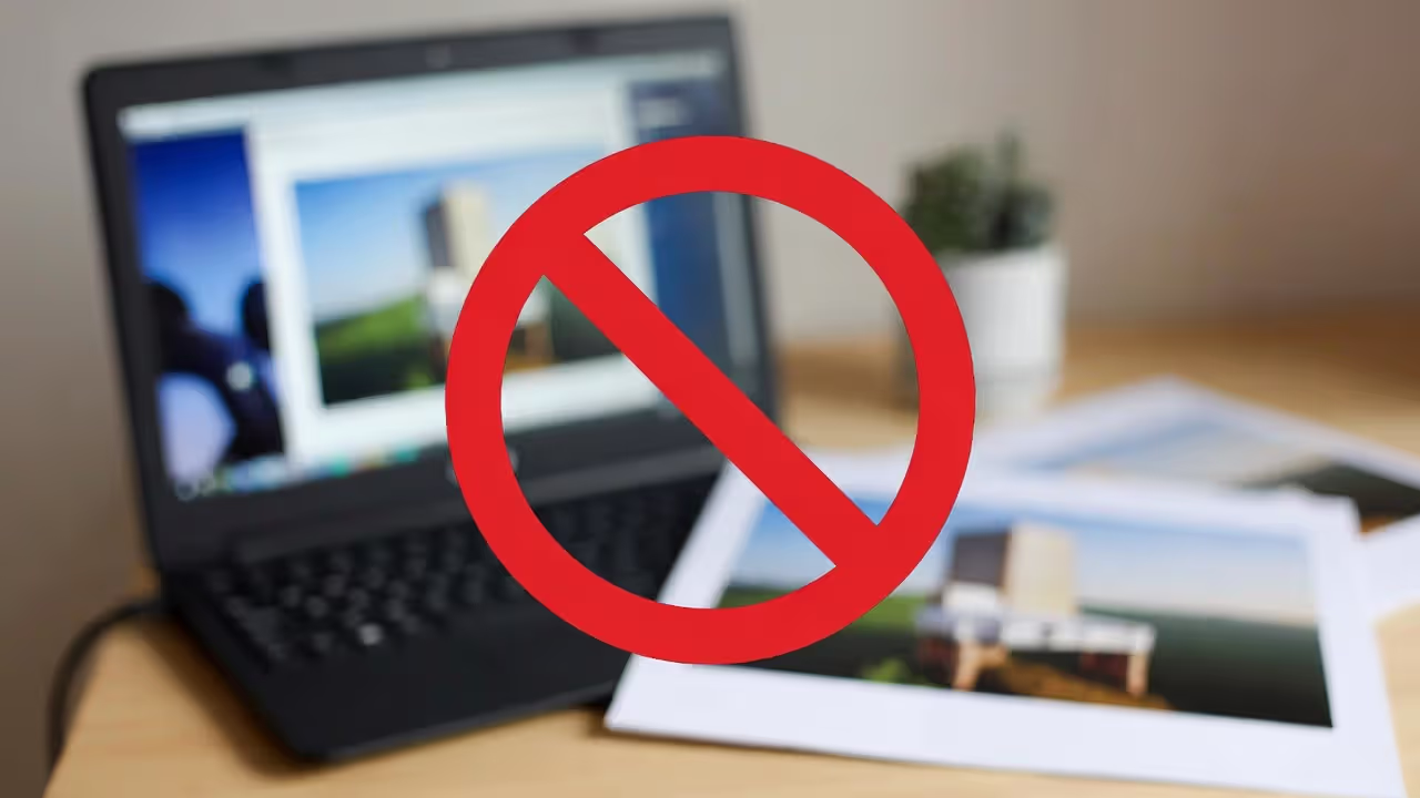 Laptop and printed image with prohibition symbol, illustrating copyright infringement risk.