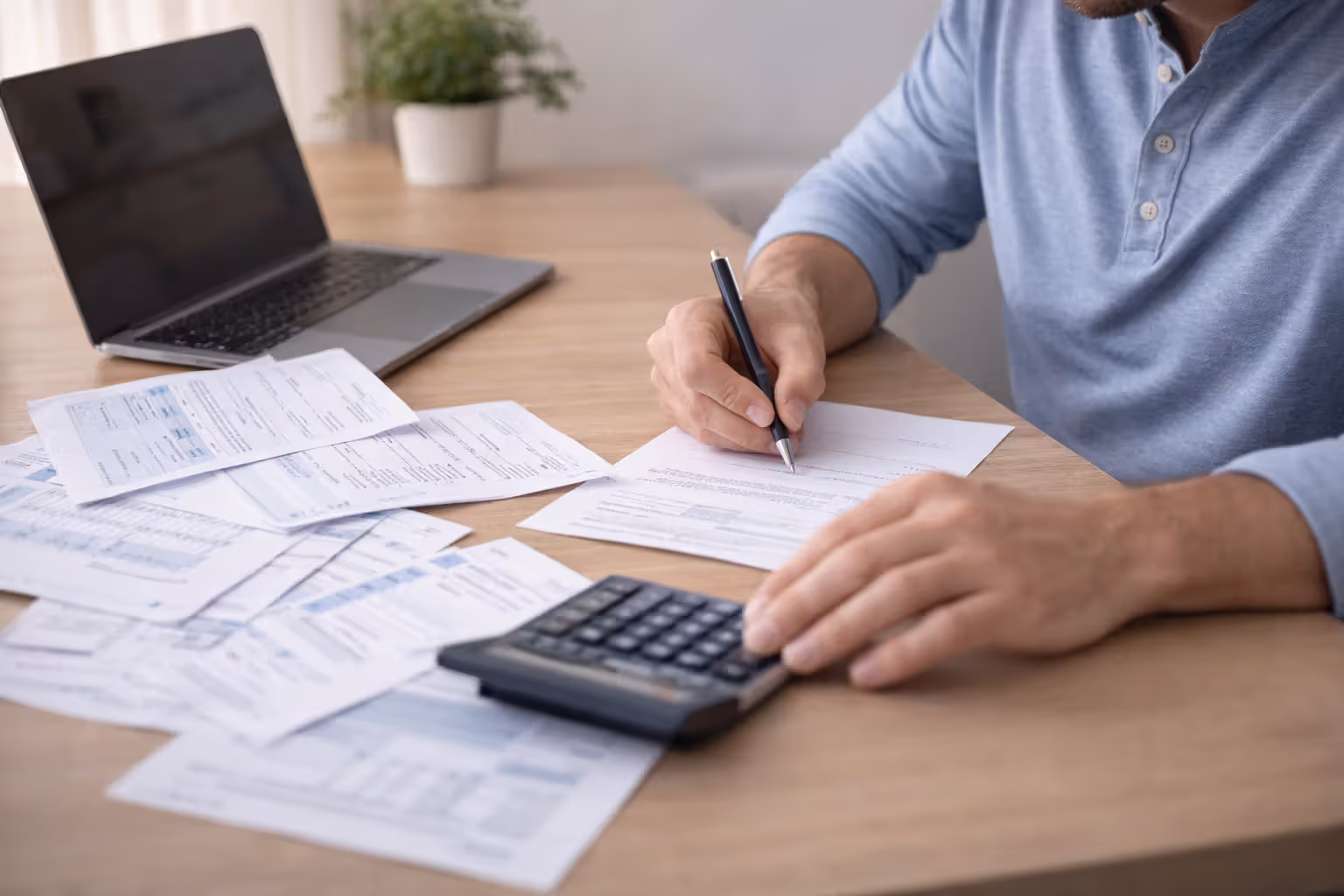 Person reviewing bills and financial statements at a home desk